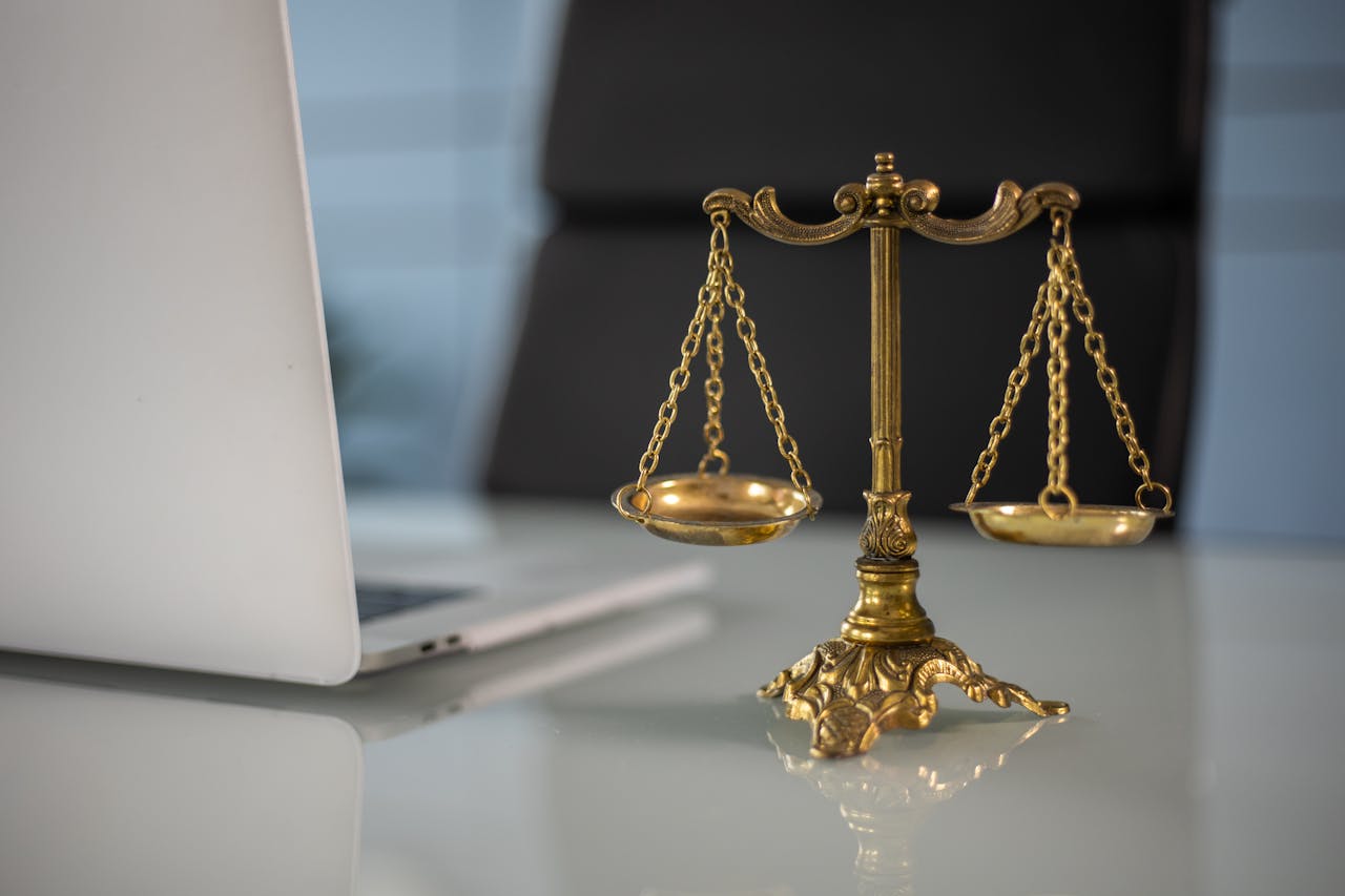 Home Golden justice scales on a desk beside a laptop, symbolizing law and balance.